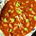 A bowl of creamy and spiced rajma masala garnished with coriander.(मसालेदार और क्रीमी राजमा मसाला की कटोरी, हरे धनिये से सजी हुई|